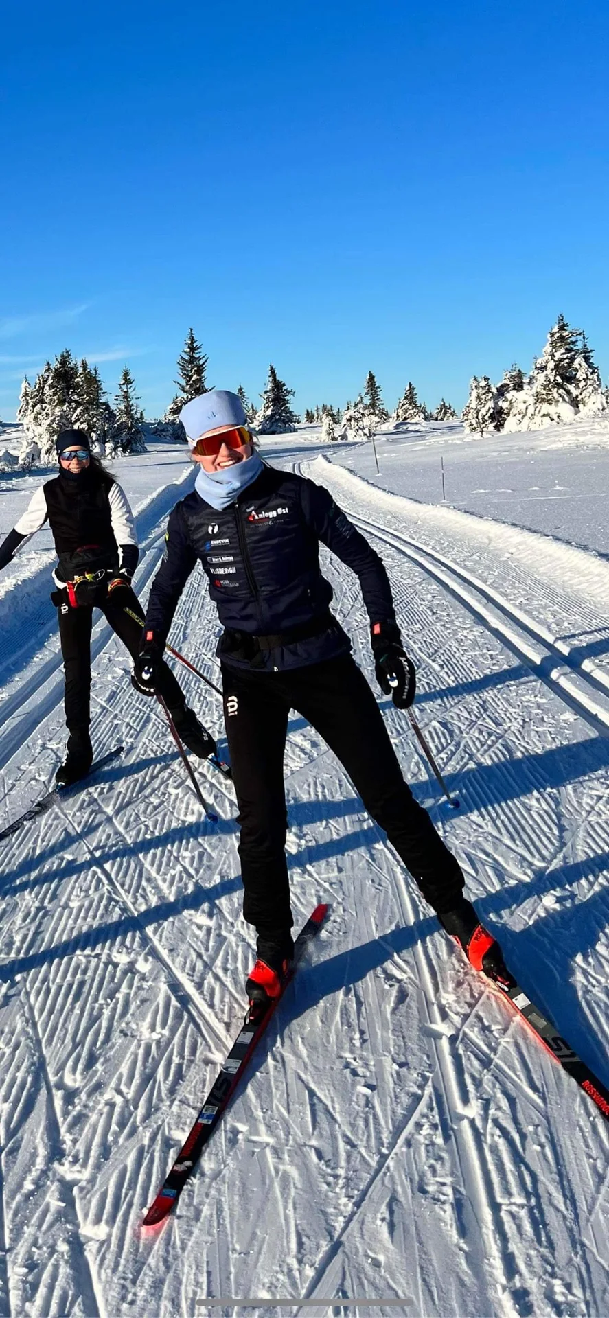 Karoline Grøtting skiing on groomed trails, with another skier behind